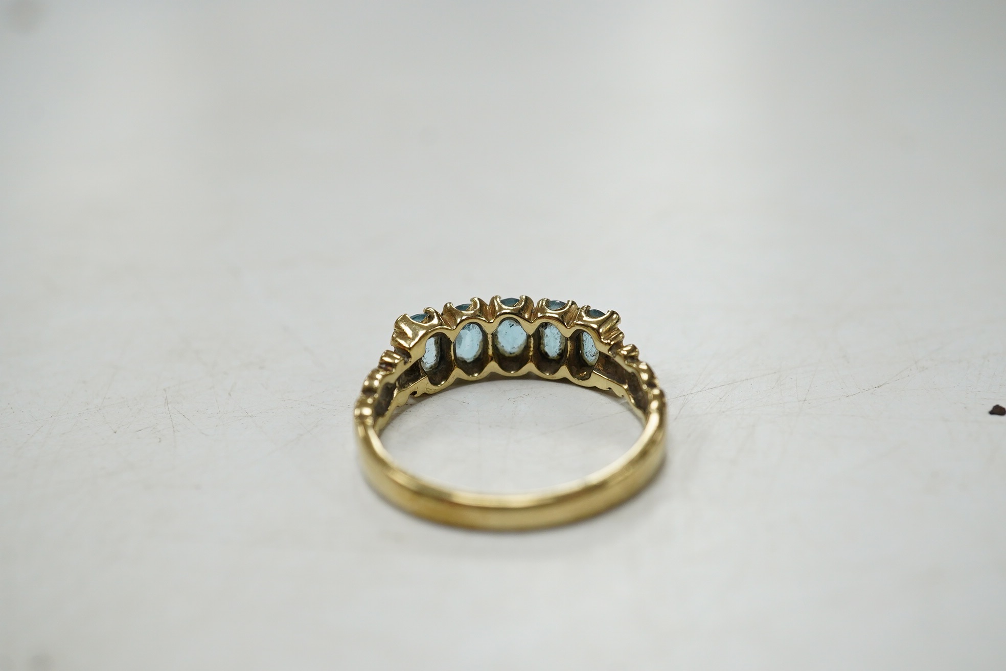 A modern 9ct gold and five stone oval cut blue topaz set half hoop ring, size N/O, gross weight 2.7 grams. Condition - poor to fair